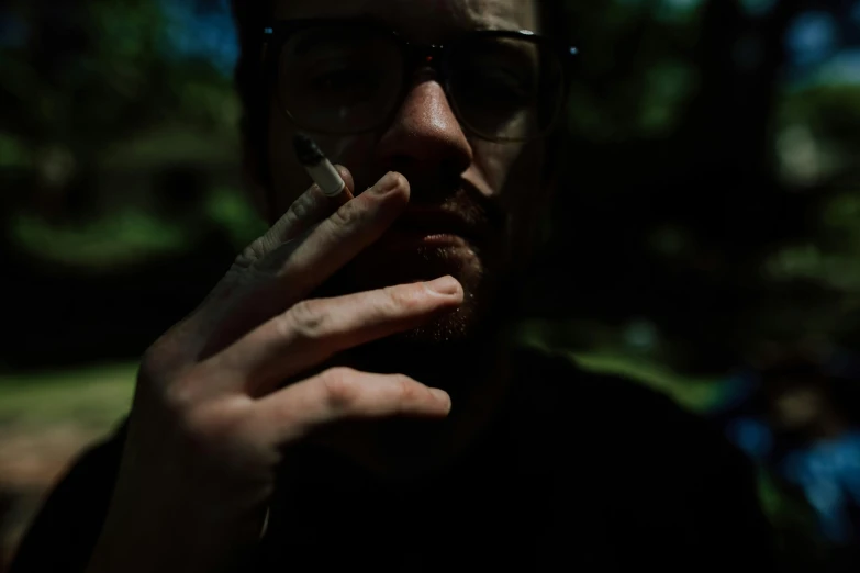 a man with glasses talking on a cell phone, inspired by Elsa Bleda, unsplash, hyperrealism, outside alone smoking weed, in a dark forest low light, portrait close - up, album cover