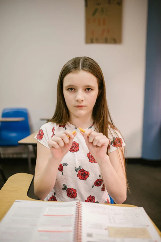 a girl sitting at a table in front of a book, holding syringe, standing in class, shot on sony a 7 iii, high quality photo