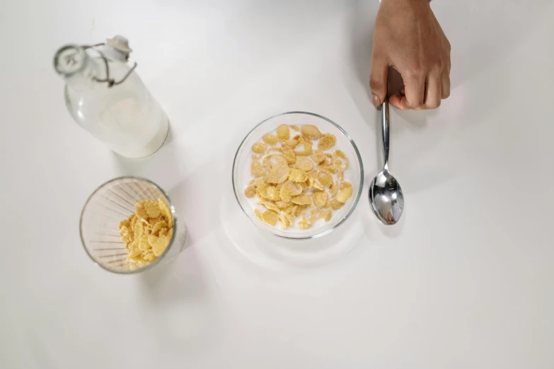 a person holding a spoon over a bowl of cereal, cinematic shot ar 9:16 -n 6 -g, plating, milk, on a white table