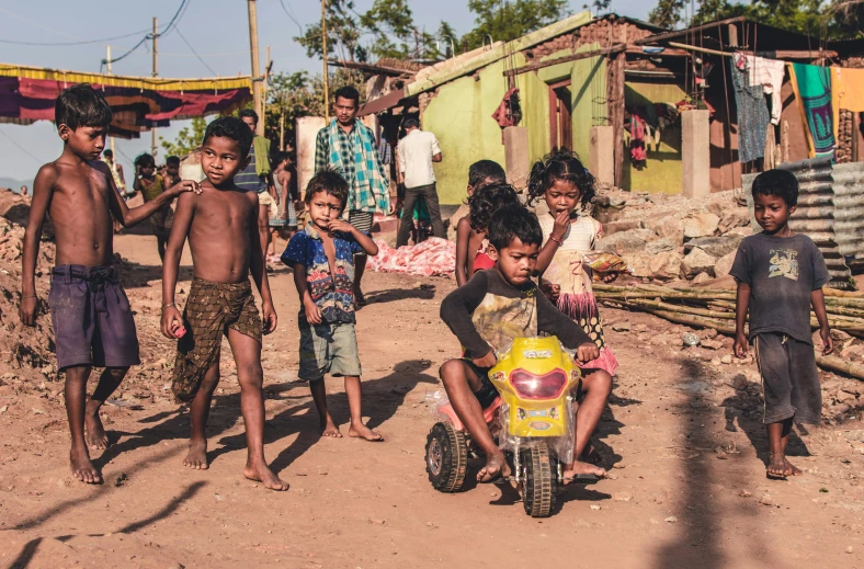 a group of children standing next to each other on a dirt road, pexels contest winner, happening, assamese aesthetic, riding a motorbike down a street, broken toys are scattered around, makeshift houses