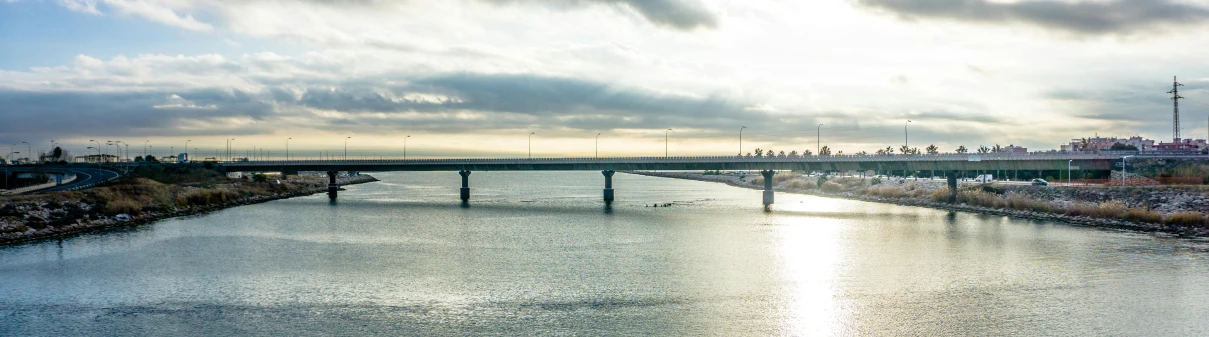 a bridge over a body of water under a cloudy sky, by Okada Hanko, unsplash, hurufiyya, overpass, 1980s photo, listing image