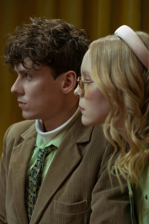 a couple of people sitting next to each other, inspired by Wes Anderson, trending on pexels, renaissance, pale skin curly blond hair, green suit and bowtie, school class, costumes from peaky blinders