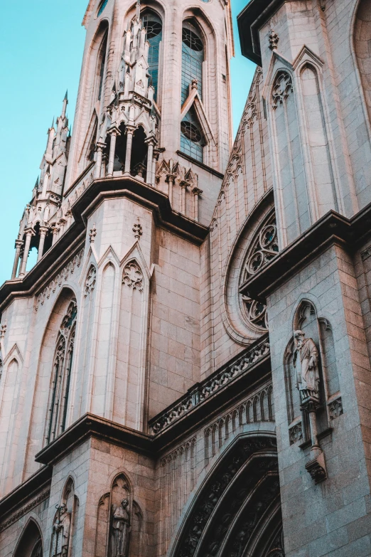 a tall building with a clock on top of it, by Gaudi, pexels contest winner, church cathedral, albuquerque, faded colors, buttresses