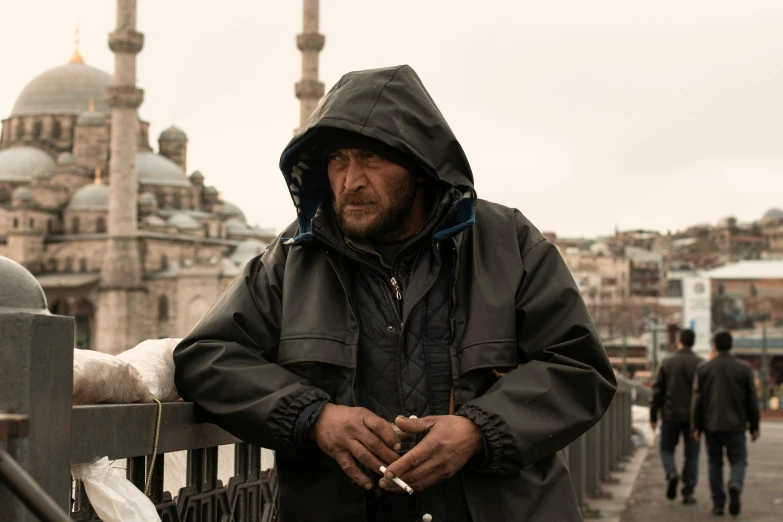 a man standing on a bridge with a cigarette in his hand, by Matija Jama, pexels contest winner, hyperrealism, ottoman sultan, movie still of a tired, hooded, ian mcshane