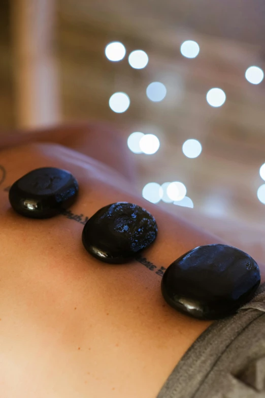 a woman getting a hot stone massage at a spa, a tattoo, by Sam Black, unsplash, ((rocks)), lights, cornwall, backdrop