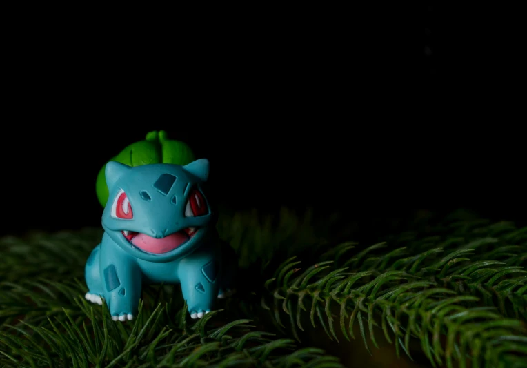 a small toy sitting on top of a pine tree, a hologram, bulbasaur, high-quality photo, very dark background, made of clay