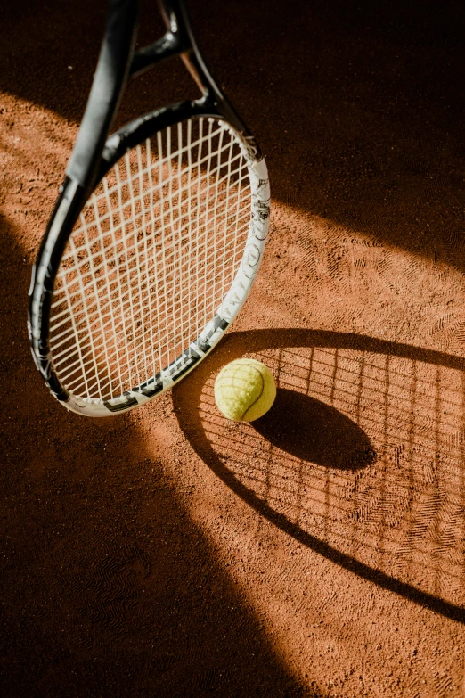 an image of tennis racket and a ball on the ground