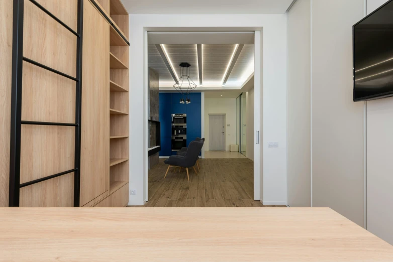 a flat screen tv sitting on top of a wooden table, by Adam Marczyński, unsplash contest winner, light and space, lacquered oak reception desk, steel archways, blue accents, white wall coloured workshop