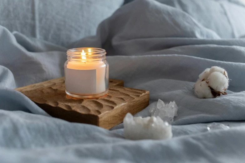 a candle sitting on top of a wooden tray on a bed, unsplash, light and space, close up of single sugar crystal, miniature product photo, centred, rippled white landscape