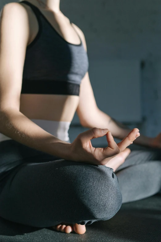 a woman sitting in the middle of a yoga pose, by Carey Morris, trending on pexels, figuration libre, hand gesture, low quality photo, low detail, sports clothing