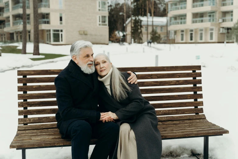 a man and woman sitting on a bench in the snow, a colorized photo, by Emma Andijewska, pexels contest winner, photorealism, gray hair and beard, embracing, lifestyle, white haired