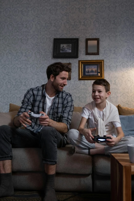 a man and a boy sitting on a couch playing a video game, sony pictures, fatherly, ad image, romance