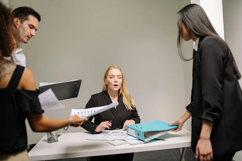 a group of people standing around a table, on a desk