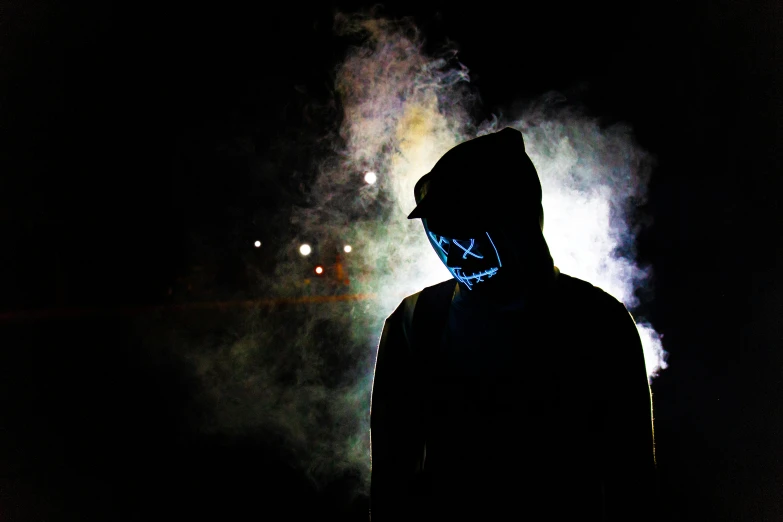 a person wearing a neon mask in the dark, an album cover, pexels contest winner, dark hat, dramatic backlight, background ( dark _ smokiness ), eyeless watcher