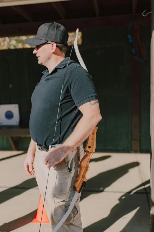 a man is holding a bow and arrow, featured on reddit, wearing pants and a t-shirt, profile image, bullpup, ready to model