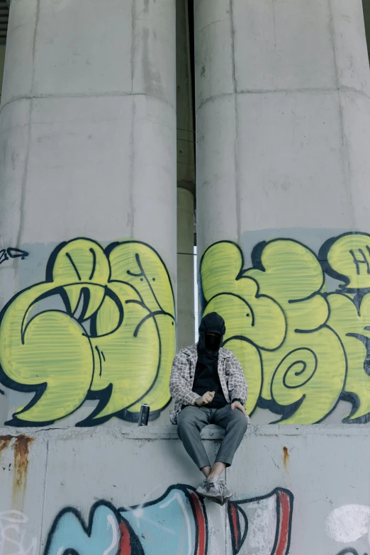 a man sitting on top of a wall covered in graffiti, concrete pillars, calmly conversing 8k, very sad c 12.0, large)}]