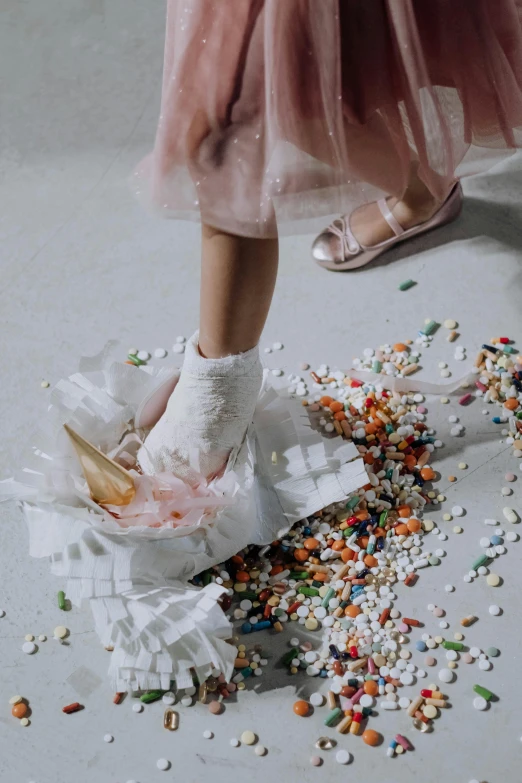 a person standing on a floor covered in confetti sprinkles, white shoes, scattered glass shards, at a fashion shoot, snacks