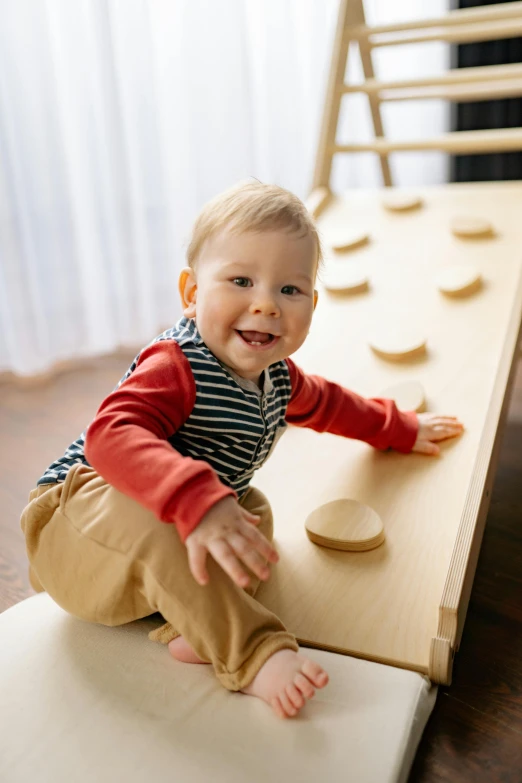 a baby sitting on top of a wooden slide, inspired by Isamu Noguchi, children playing with pogs, smiling, natural wood top, smooth technology