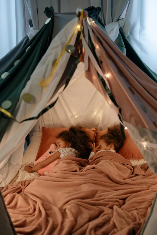 a couple of kids laying on top of a bed, by Jessie Algie, pexels contest winner, interior of a tent, romantic themed, 4k), designed for cozy aesthetics!