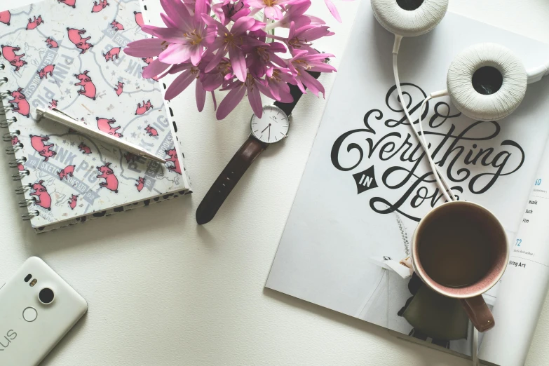 a book sitting on top of a table next to a cup of coffee, a photo, “modern calligraphy art, 9 9 designs, flowery wallpaper, magazine photo