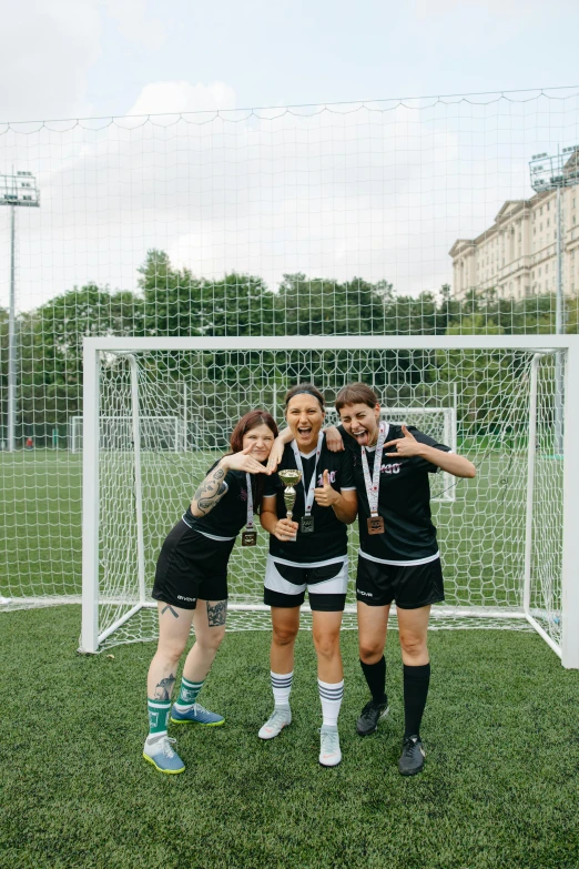 a group of girls standing in front of a soccer goal, by Attila Meszlenyi, unsplash contest winner, renaissance, cups and balls, non-binary, posing for camera, award wining photo