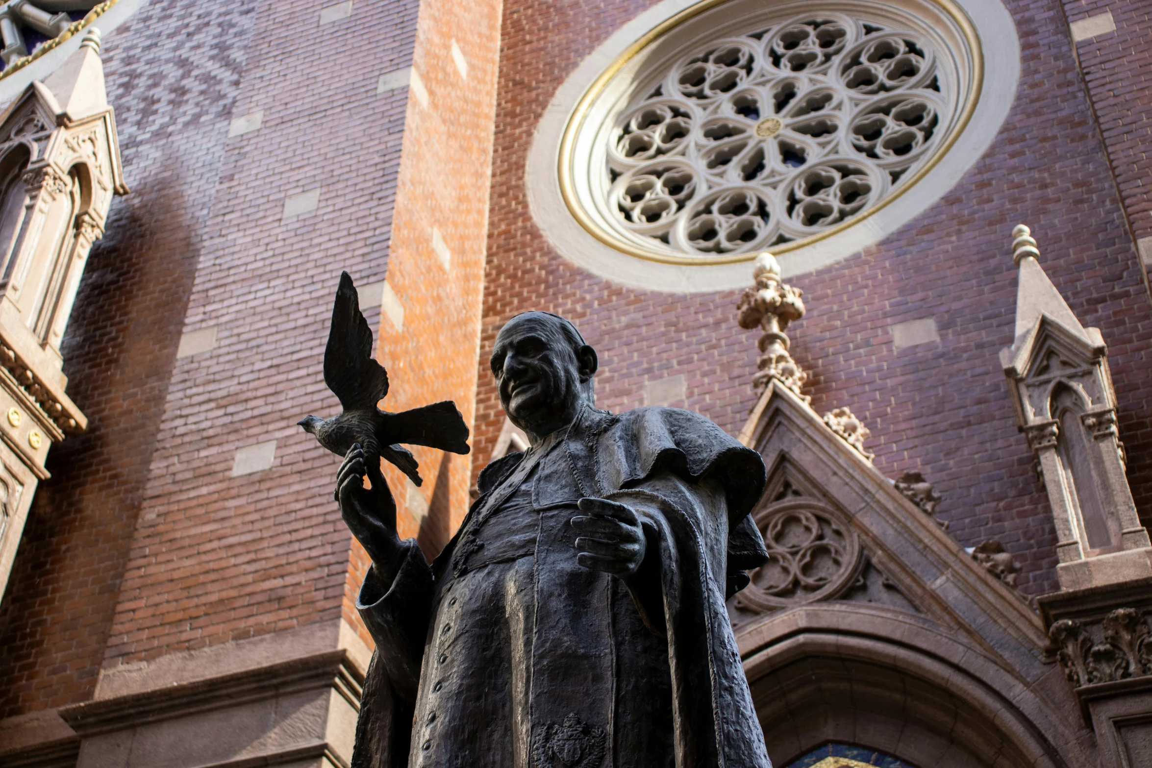 a statue of a man holding a bird in front of a church, a statue, inspired by Thomas Aquinas Daly, pexels contest winner, joaquin sorolla, with an intricate, brown, ny