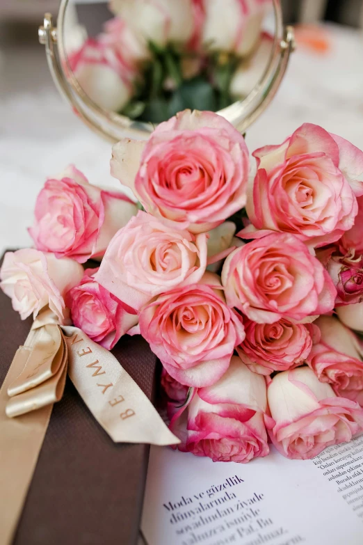 a bouquet of pink roses sitting on top of a book, by Hyman Bloom, pink and gold, loving embrace, creamy, pink accents