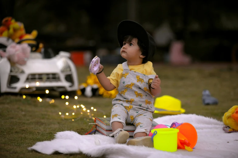 a small child sitting on top of a blanket, by Bernardino Mei, pexels, fairy lights, having a picnic, yellow, cinematic outfit photo