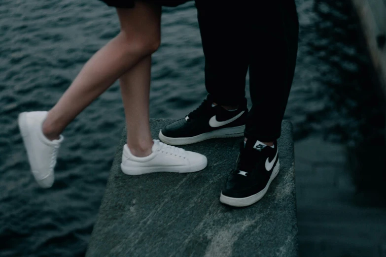 a couple standing next to each other near a body of water, by Niko Henrichon, pexels contest winner, realism, sneaker shoes, white and black, 15081959 21121991 01012000 4k, plain background
