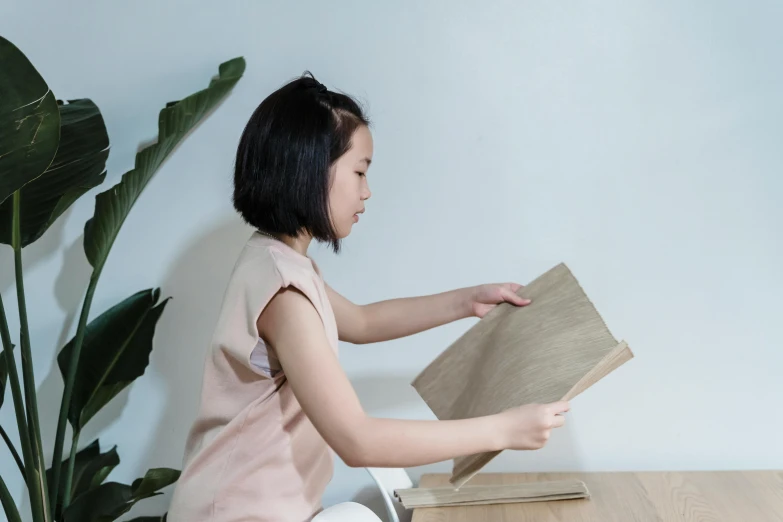 a little girl sitting on the floor reading a book, a picture, inspired by Kim Du-ryang, pexels contest winner, mingei, minimalist furniture, natural wood top, standing sideways, stopmotion animation