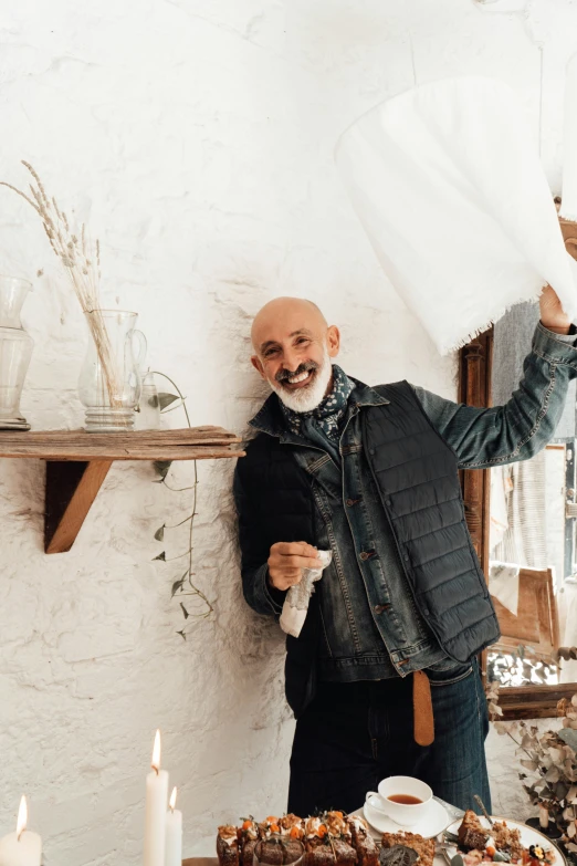 a man that is standing in front of a table, inspired by Giuseppe Camuncoli, trending on unsplash, arts and crafts movement, white cloth in wind shining, rustic and weathered, smiling man, gaspar noe