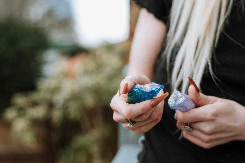 a close up of a person holding something in their hands, a marble sculpture, trending on pexels, amethyst citrine opal, blue, teenage girl, exterior shot