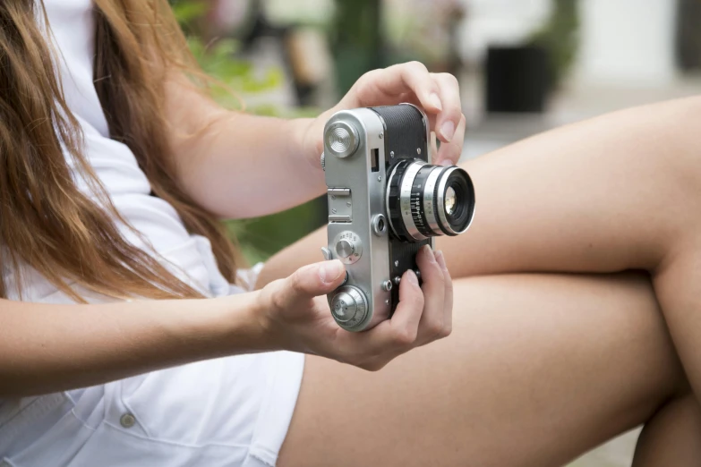 a close up of a person holding a camera, a picture, inspired by Ruth Orkin, pexels contest winner, photorealism, thighs focus, instagram model, panasonic 35mm, in summer