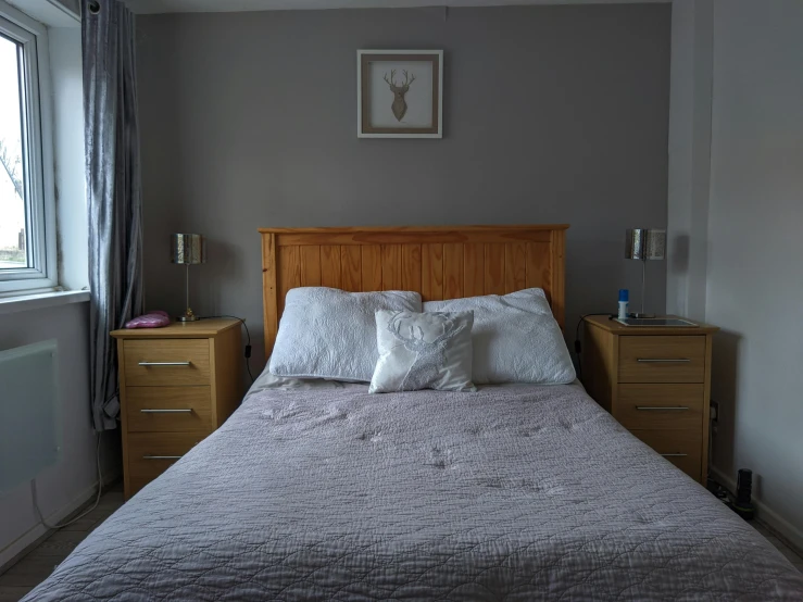 a bed sitting in a bedroom next to a window, inspired by Bedwyr Williams, grey and silver, wooden furniture, low quality photo, family friendly