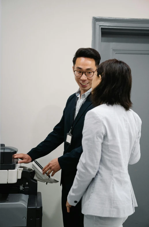 a man and a woman standing in front of a printer, by Jang Seung-eop, unsplash, low quality photo, teaching, hwang se - on, 15081959 21121991 01012000 4k