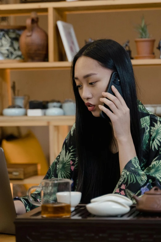 a woman sitting at a table talking on a cell phone, inspired by helen huang, happening, using a macbook, ethnicity : japanese, curated collections, premium quality