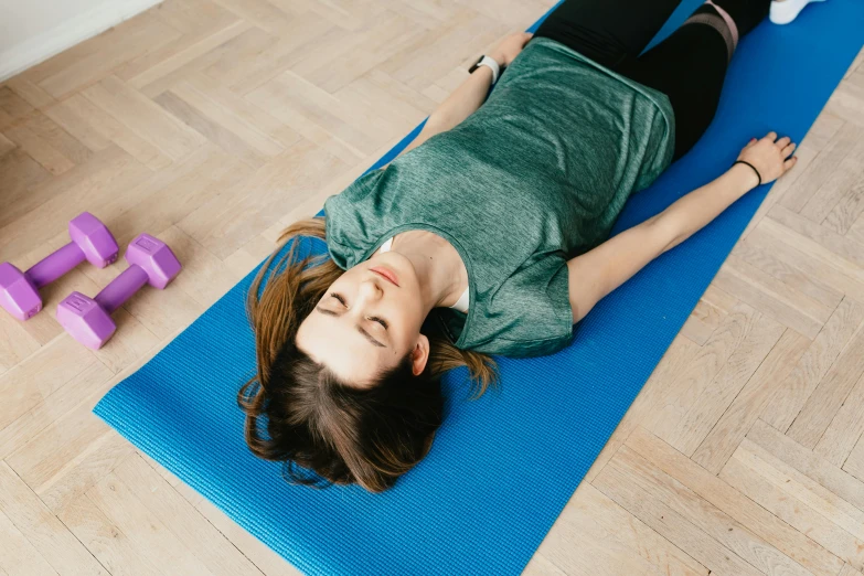 a woman laying on her stomach on a yoga mat, by Rachel Reckitt, trending on pexels, hurufiyya, looking across the shoulder, high quality photo, ad image, thumbnail