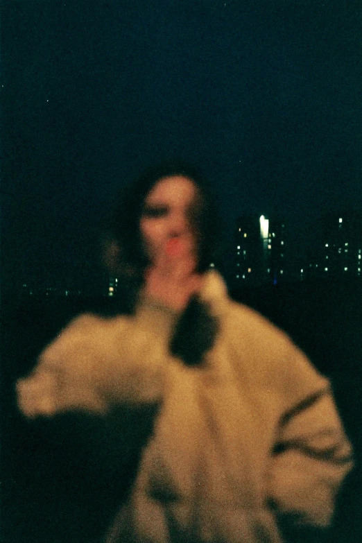 a woman standing in front of a city at night, an album cover, tonalism, obscured face, shot onfilm, loosely cropped, pale woman