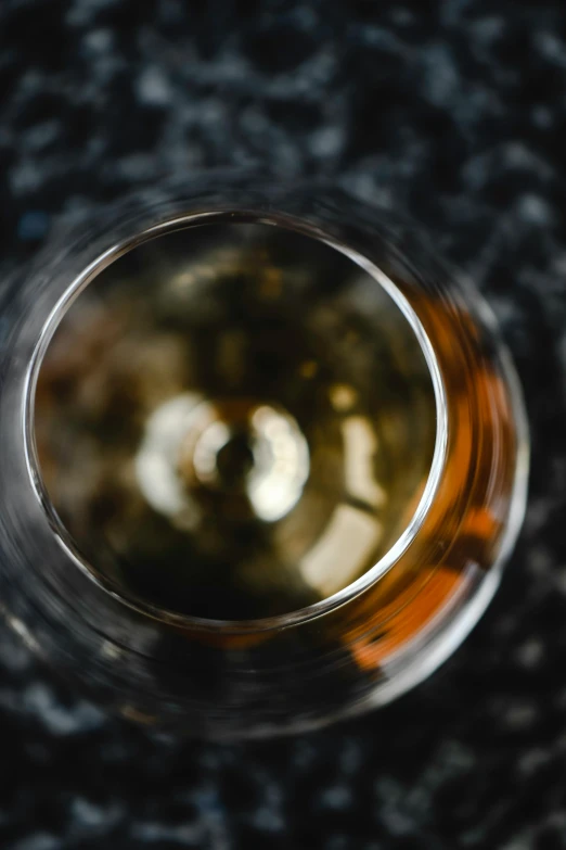 a close up of a glass of wine on a table, by Andrew Domachowski, unsplash, close-up from above, glass with rum, multiple stories, whisky