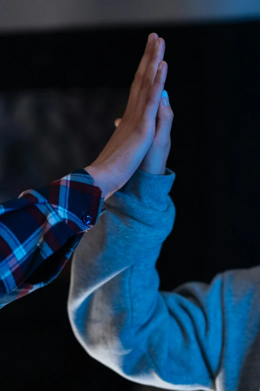 a man is giving a high five with his hands, a hologram, by James Morris, unsplash, portrait of max caulfield, praying, two young men, low-light photograph