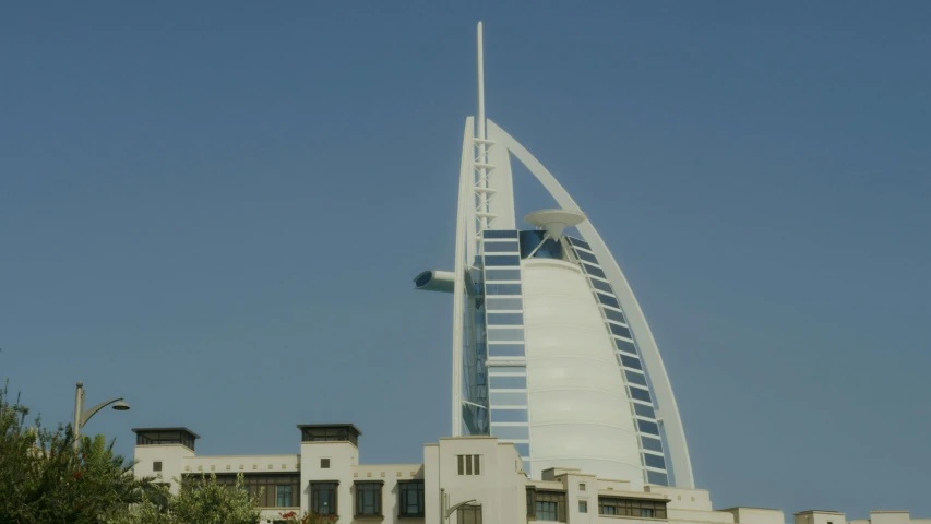 a tall building sitting on top of a lush green hillside, inspired by Victor Enrich, pexels contest winner, hurufiyya, ships with sails underneath, gta : dubai, front side view, 2 0 0 4 photograph