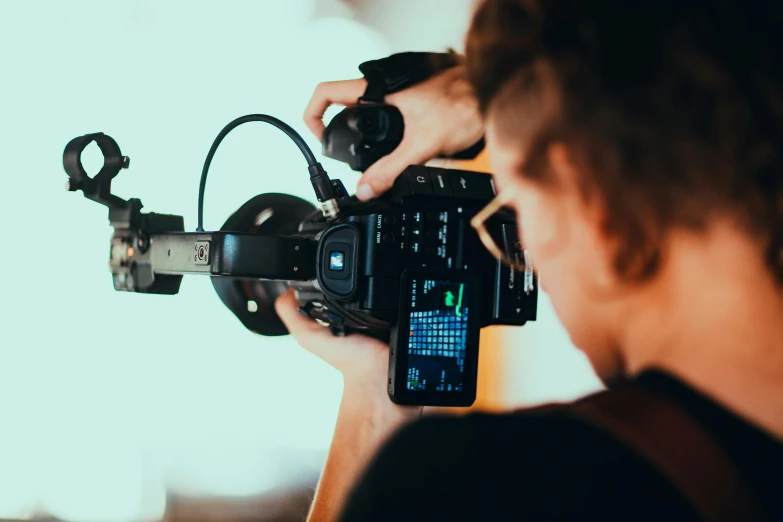 a close up of a person holding a camera, trending on pexels, video art, filmic lighting, facing away from camera, background canon, avatar image