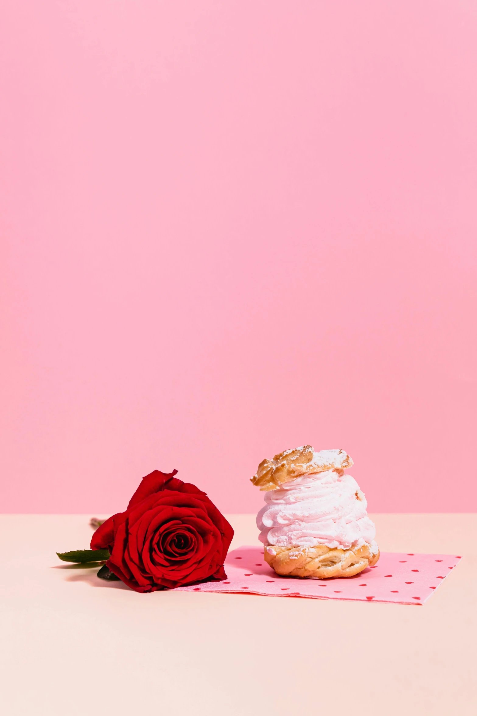 a cupcake sitting on top of a table next to a red rose, a still life, by Julia Pishtar, romanticism, pink and gold, ice cream on the side, official product photo, crisp contour - lines