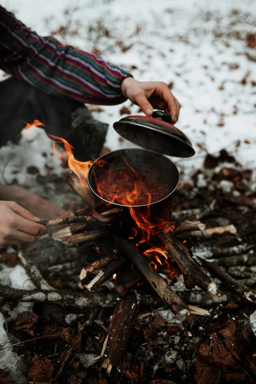 a man cooking over an open fire in the snow, pexels contest winner, fan favorite, burning water, male and female, brown