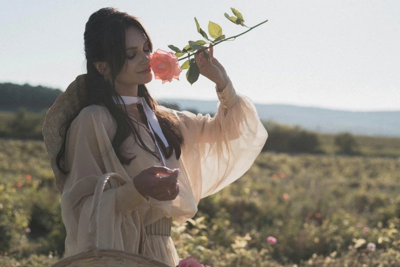 a woman standing in a field holding a rose, pexels contest winner, wearing a luxurious silk robe, dreamy mila kunis, having a picnic, blanca alvarez