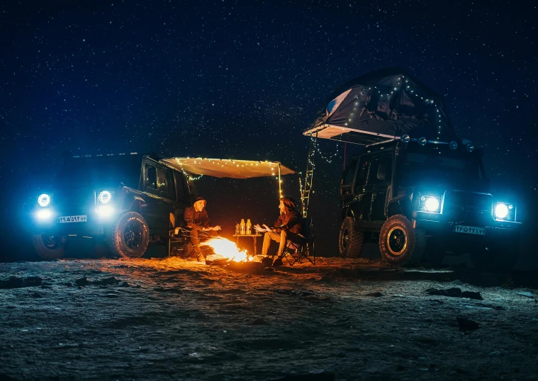 a group of people sitting around a campfire under a tent, by Julia Pishtar, unsplash contest winner, vehicle photography, cybertruck, australian winter night, panorama shot