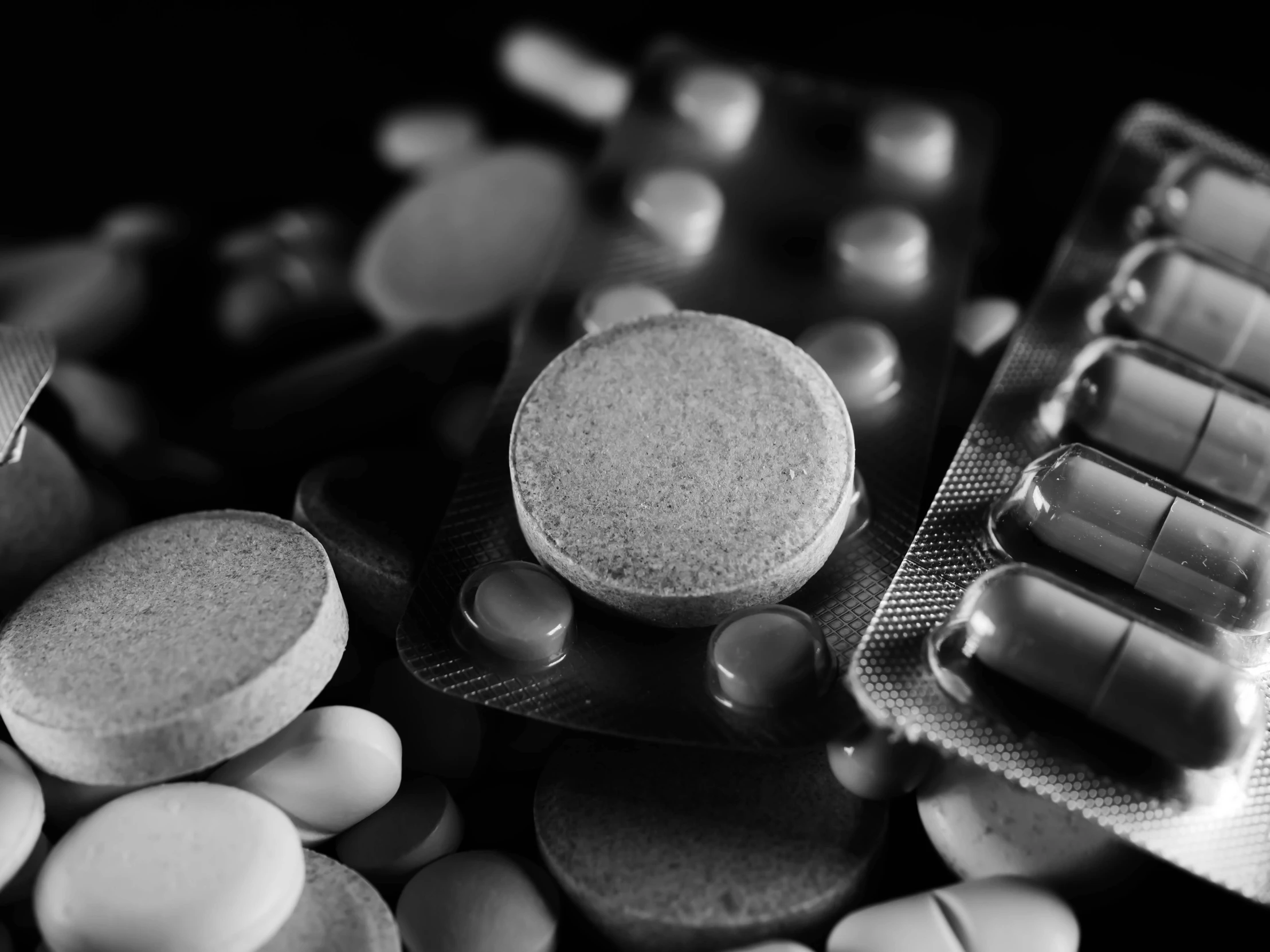 a bunch of pills sitting on top of a table, a black and white photo, by Adam Marczyński, plasticien, uploaded, set photo, closeup photo, detailed product photo
