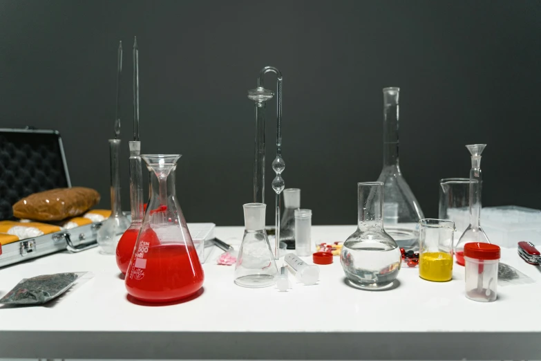 a group of glassware sitting on top of a white table, analytical art, underground lab, replicas, red liquid, hegre