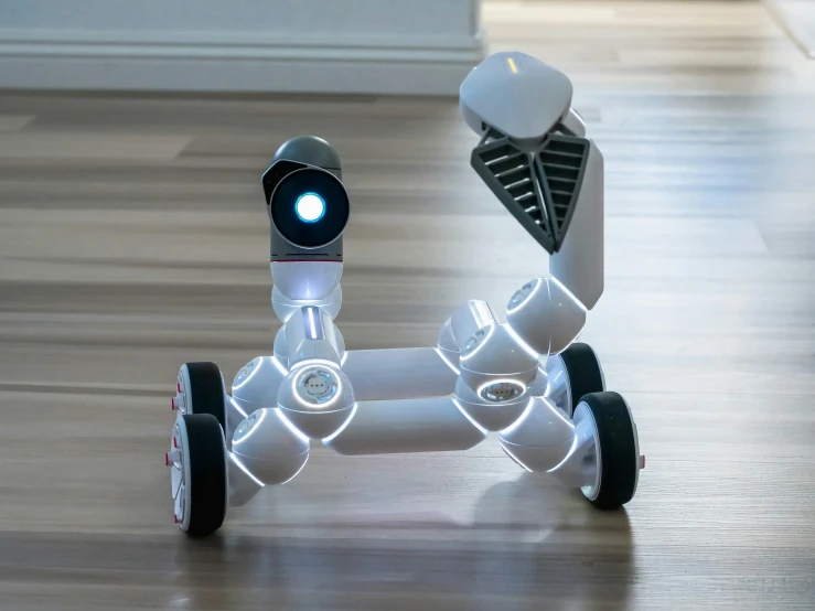 a couple of robots sitting on top of a wooden floor, lightshow, salvia droid, sleek white, front angle