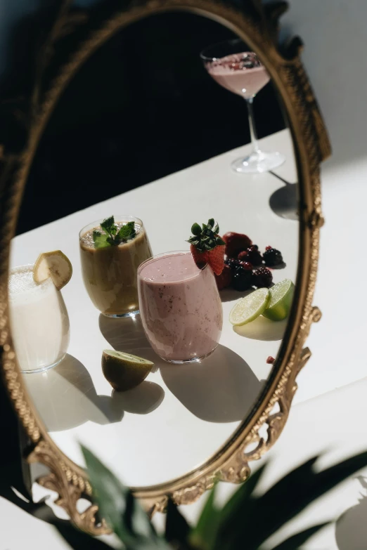 a mirror sitting on top of a table next to a plant, a still life, inspired by Jacopo Bellini, unsplash, renaissance, drink milkshakes together, fruit, low quality photo, magnificent oval face